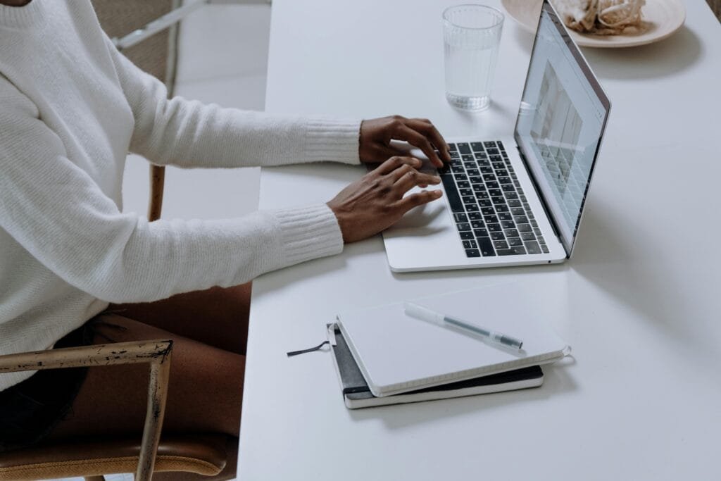 Une personne tapant sur un ordinateur portable dans un bureau à domicile minimaliste, capturant la culture de travail moderne.