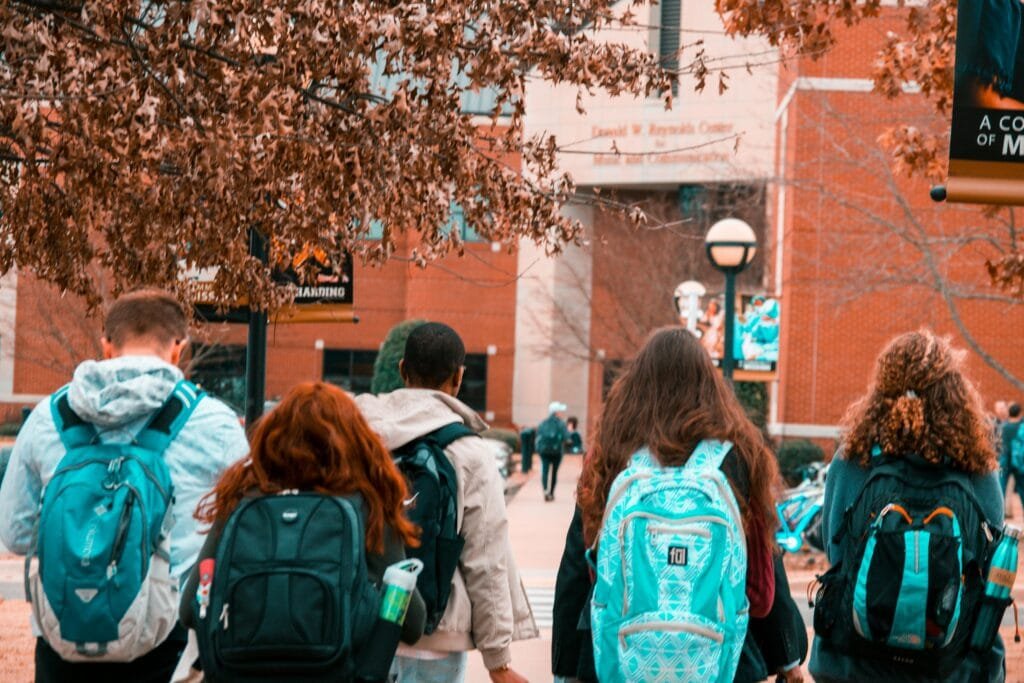 Un groupe d'étudiants avec des sacs à dos marchant ensemble à l'extérieur sur le campus.