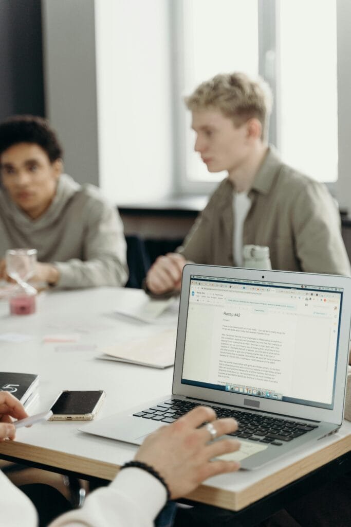 Groupe de jeunes adultes travaillant ensemble dans un bureau moderne, se concentrant sur un ordinateur portable.