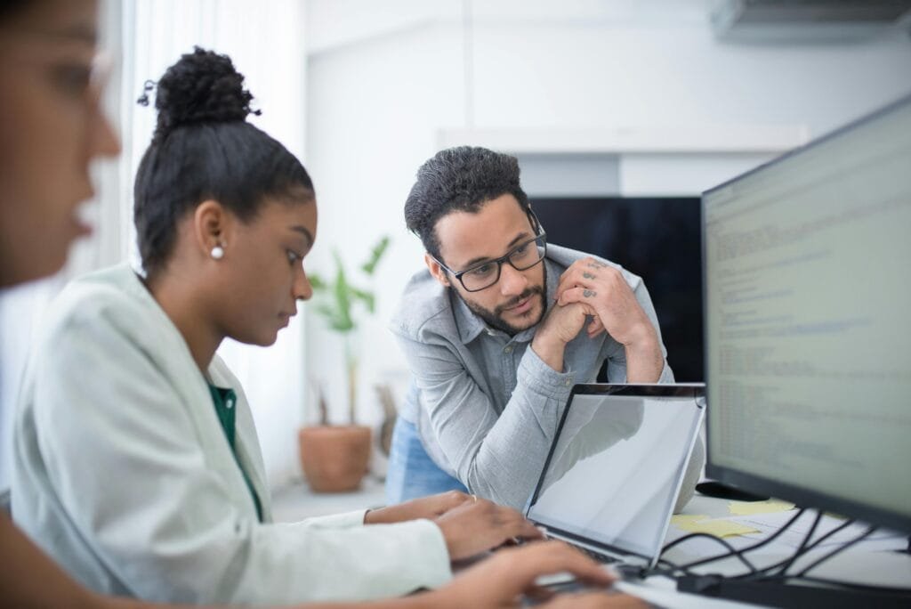 Deux personnes collaborent dans un bureau moderne, axé sur le travail informatique